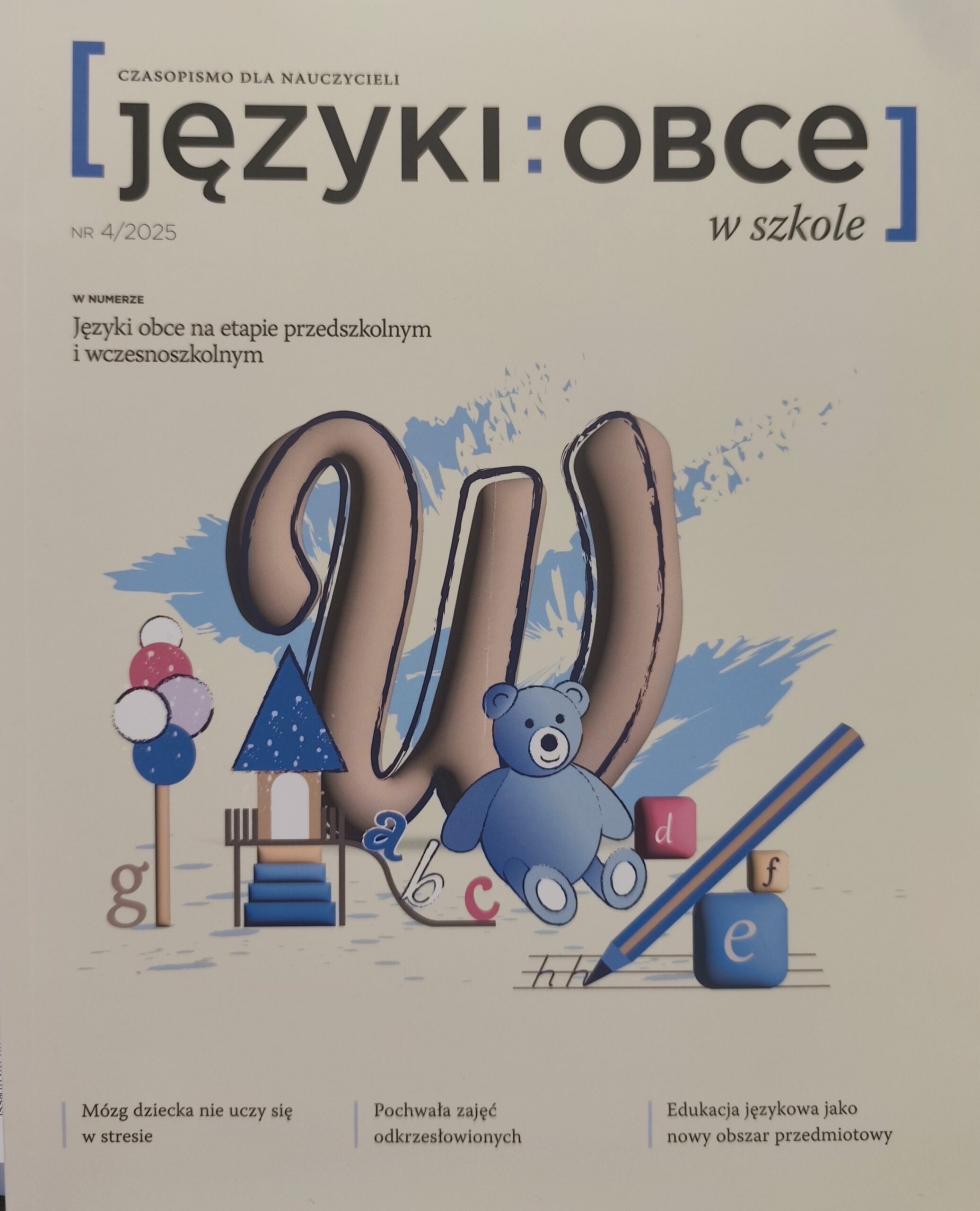 Pastelowe żółte tło. Wielka litera W. Przed literą stoją zbudowane z drewnianych klocków: drzewo, domek. Obok siedzi niebieski pluszowy miś.